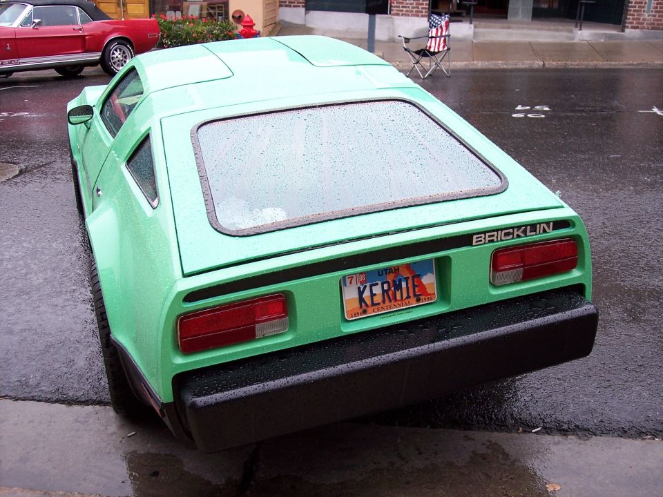 Rear of a green Bricklin coupe with Utah KERMIE plate on a wet street