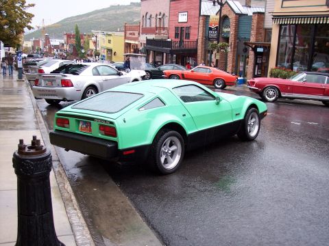 1972 Ford Ranchero - A green and black car with a unique angular design is parked on a wet street, with other vehicles visible.