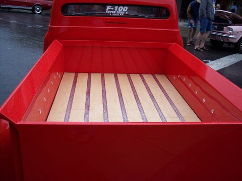 1972 Ford Ranchero - A red pickup truck with a newly finished wood-slat bed is parked next to other vehicles.