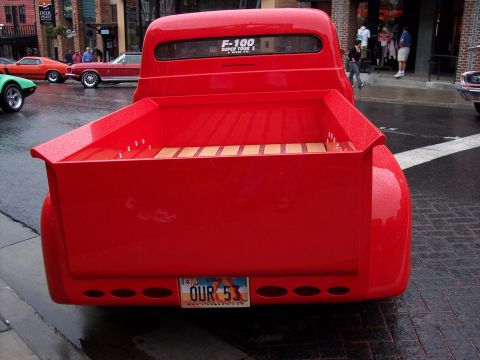 1972 Ford Ranchero - A red pickup truck with a wooden bed is parked on a wet street.