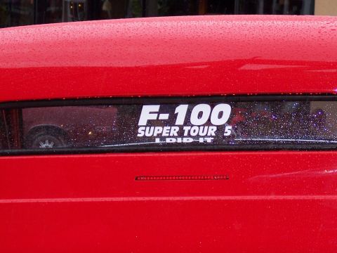 1972 Ford Ranchero - A red vehicle displays an F-100 SUPER TOUR 5 decal on its rear window.