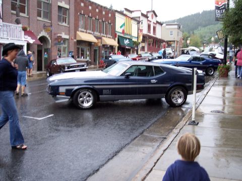 1972 Ford Ranchero - A 1971 Ford Mustang Mach 1 is seen on a wet street in a town with brick buildings.