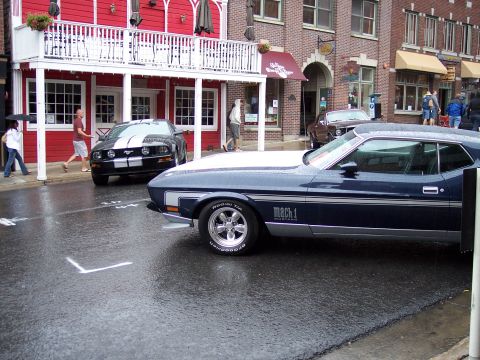 1972 Ford Ranchero - A dark blue 1971 Ford Mustang Mach 1 is seen from the side on a wet street, with a black Mustang in the background.