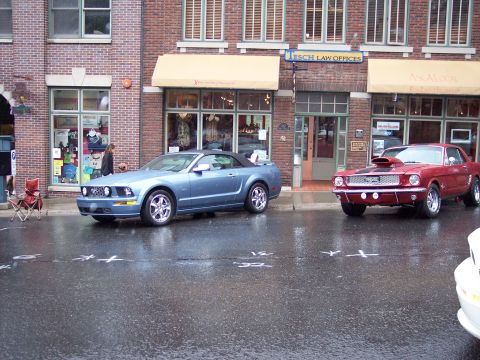 1972 Ford Ranchero - Two Ford Mustangs, a classic coupe and a modern convertible, sit parked on a wet street.