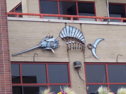 1972 Ford Ranchero - A metal sculpture of a fish is mounted on a brick building facade.