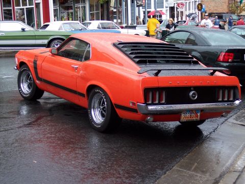 1972 Ford Ranchero - This orange 1970 Ford Mustang Boss 302 features distinctive black stripes and rear window louvers, seen here on a wet street.