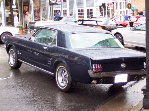 1972 Ford Ranchero - A classic Ford Mustang is parked on a wet street, with other vehicles and buildings visible.