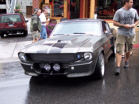1972 Ford Ranchero - Gray 1967 Ford Mustang Shelby GT500 with black racing stripes and fog lights parked on a wet street.