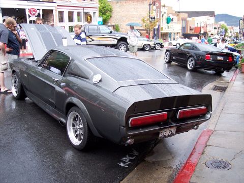 1972 Ford Ranchero - A gray 1969 Ford Mustang Shelby GT500 is parked on a wet street, with other vehicles visible in the background.