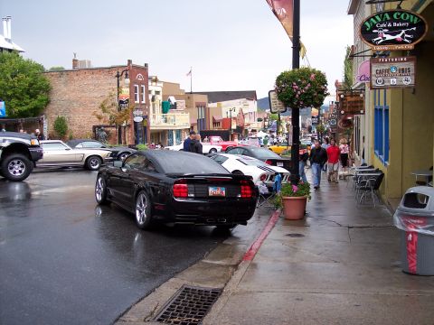 1972 Ford Ranchero - Several cars are parked along a street in front of shops on a cloudy day.