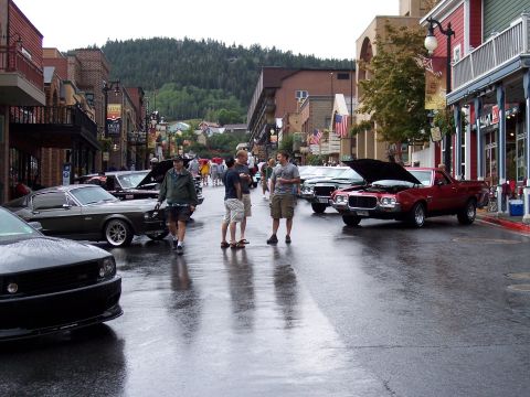 1972 Ford Ranchero - A street scene several classic cars on a rainy day, with onlookers milling about.