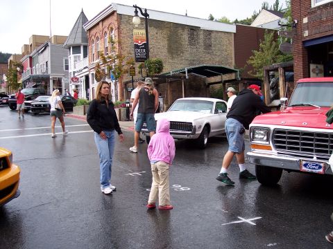 1972 Ford Ranchero - A street scene shows several vehicles and people gathered on a wet road, possibly at an event.