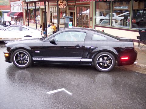 1972 Ford Ranchero - A black Shelby GT Mustang is parked on a wet street in front of a restaurant with a sign for 'Moose Grill'.