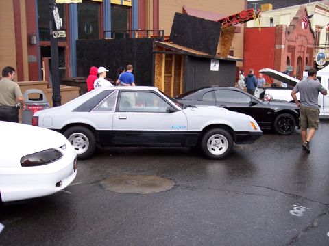 1972 Ford Ranchero - A light gray and black coupe with "COBRA" badging is parked on a wet street next to other vehicles.