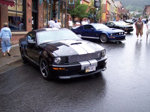 1972 Ford Ranchero - Several Ford Mustangs are parked on a wet street in a town.