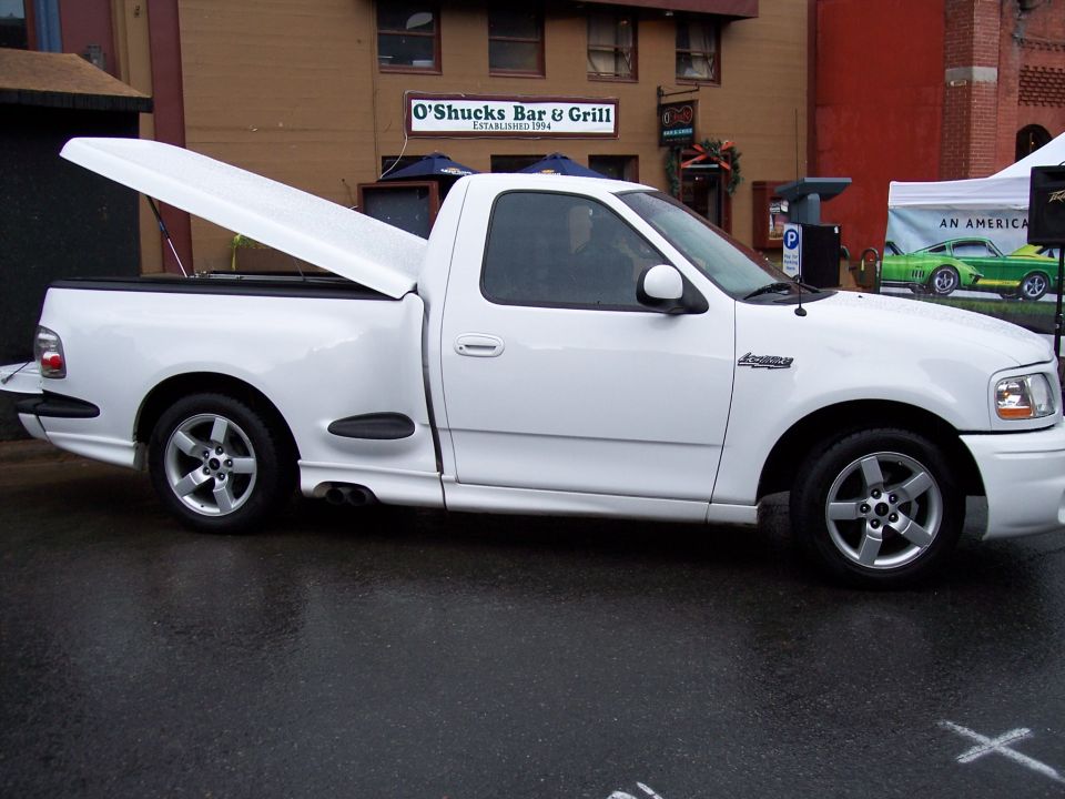 White regular-cab pickup, side view, hood open, parked outside O'Shucks Bar & Grill