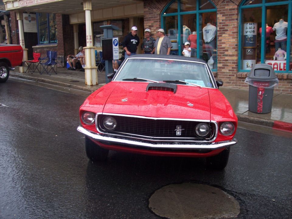 Front view of a red classic Ford Mustang on a wet street