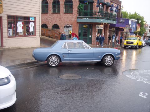 Light blue classic Mustang coupe in side view on a wet city street