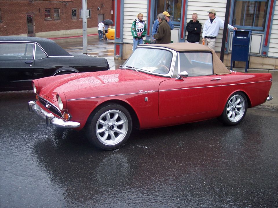 Red Sunbeam Tiger convertible with tan top on wet street
