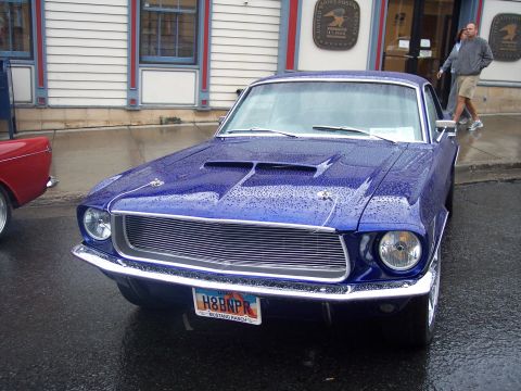 Blue vintage Ford Mustang front view with Utah H8BNPR plate on wet street