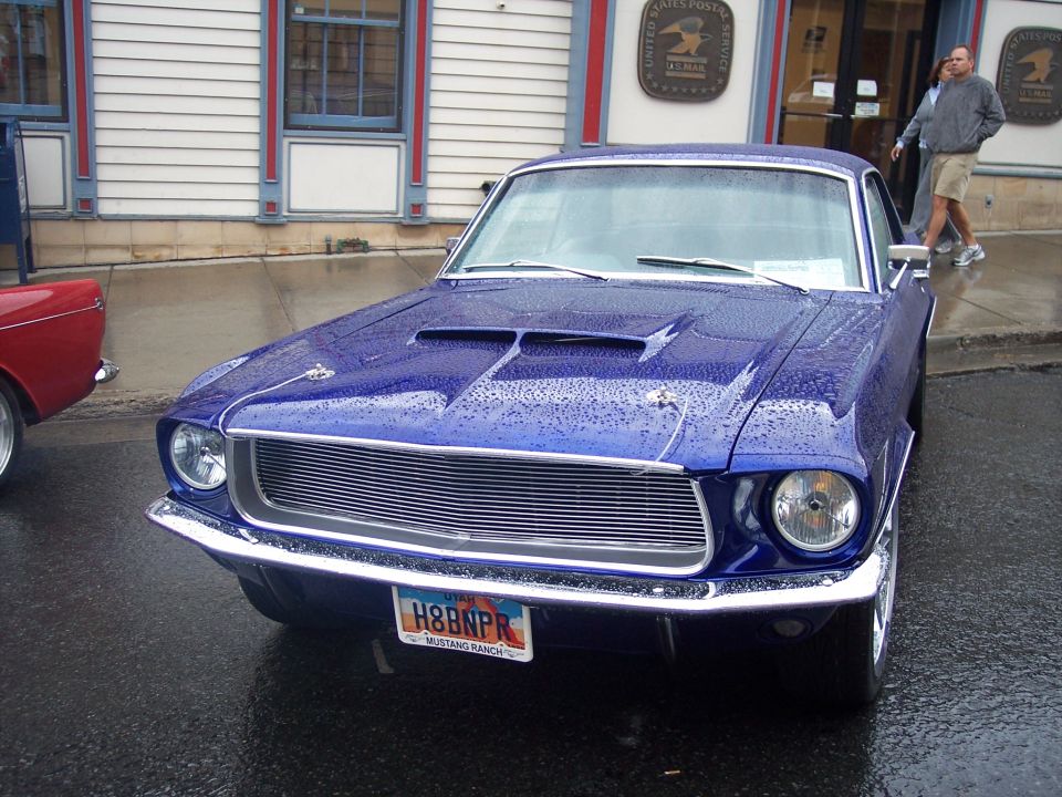 Blue vintage Ford Mustang front view with Utah H8BNPR plate on wet street