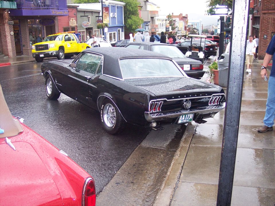 Black Ford Mustang coupe rear three-quarter view on a wet street with Utah plate AA 1730