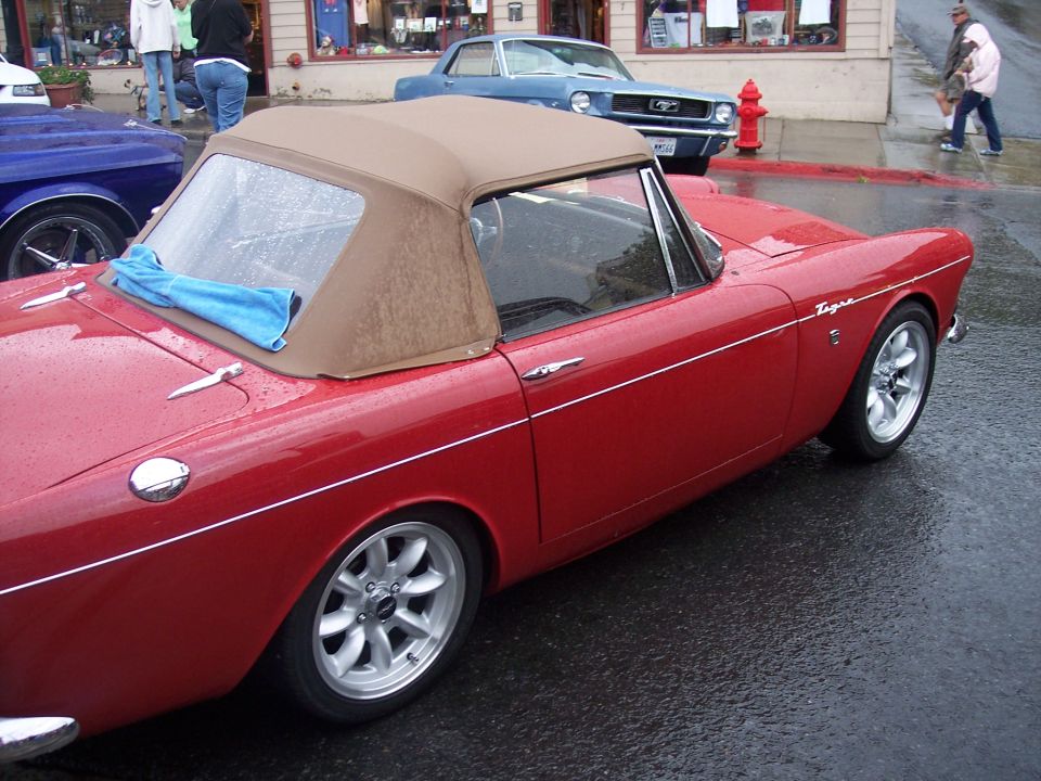 Red Sunbeam Tiger convertible with tan top on wet street