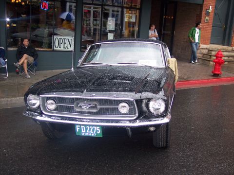 Black classic Ford Mustang, front 3/4 view, wet, with Utah plate on a city street