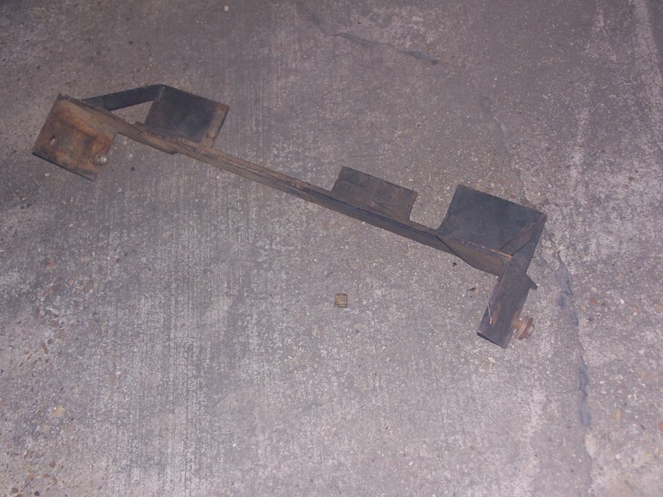 Rusty steel winch-mount bracket lying on a concrete floor