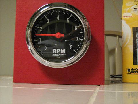1988 Mercury Grand Marquis - This Auto Meter RPM gauge is mounted on a red housing, with a yellow box visible in the background.