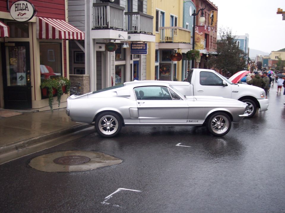 Silver Mustang fastback GT500 in side view on a wet town street