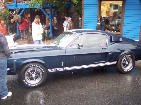 Dark blue Shelby GT500 fastback in side view on a wet street