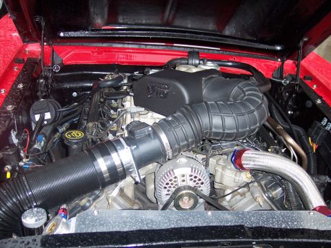 Ford V6 engine bay with black intake tube, chrome alternator, and red painted surrounds