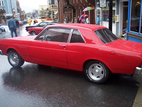 Red two-door coupe in side profile on a wet street with mag wheels and BFGoodrich tires
