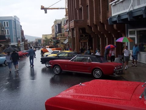 Red Mustang convertible parked on wet street at rainy classic car show