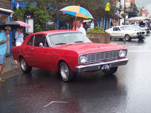 Red vintage Ford coupe, front-right view, on a wet street with a Utah plate AE 6330.