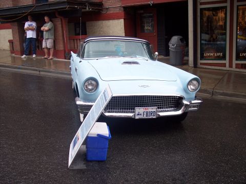 Light blue vintage Ford Thunderbird front view with Utah FBIRD plate on wet street