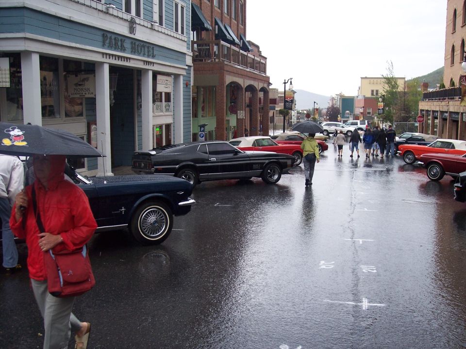 Rainy street with classic Mustangs parked by Park Hotel and people with umbrellas