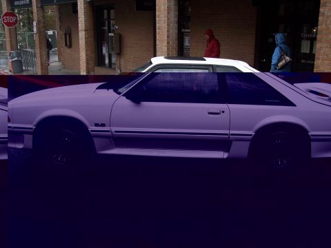 Side view of Fox-body Ford Mustang GT hatchback with white roof, parked on a wet street.