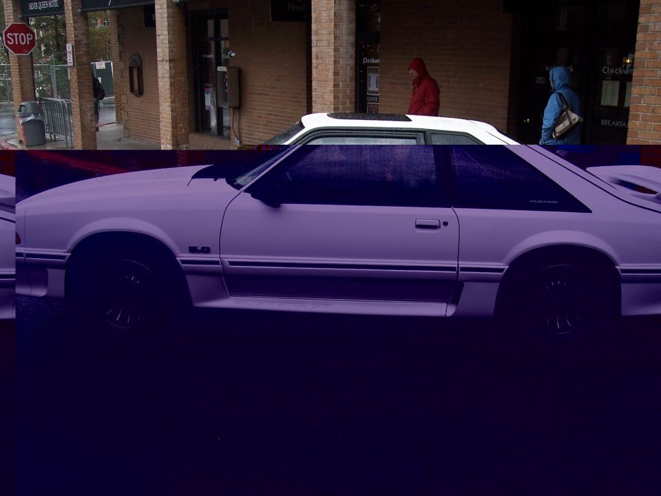 Side view of Fox-body Ford Mustang GT hatchback with white roof, parked on a wet street.