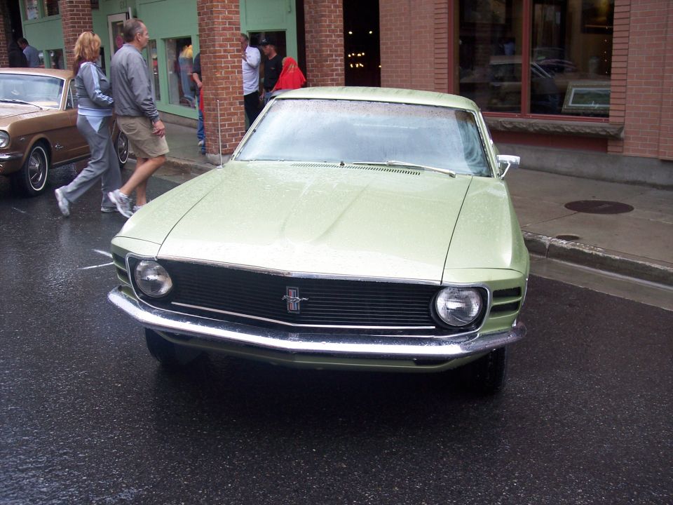 Light green classic Ford Mustang front view on wet city street