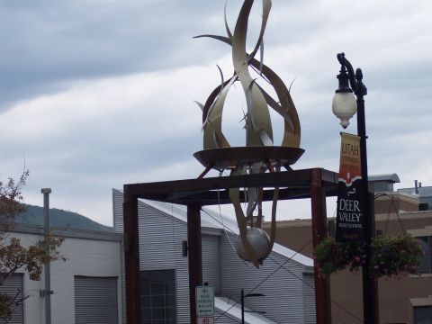 Metal flame sculpture and lamppost with Deer Valley Music Festival banner under cloudy sky