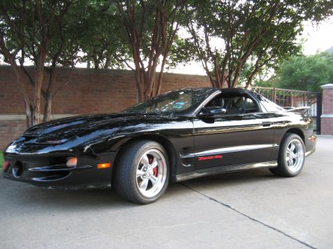 2002 Pontiac Trans Am - A black 2002 Pontiac Trans Am is parked outdoors, showing its distinctive body style and side decal.