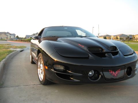 2002 Pontiac Trans Am - A black 2002 Pontiac Trans Am is parked on a concrete surface with houses in the background.