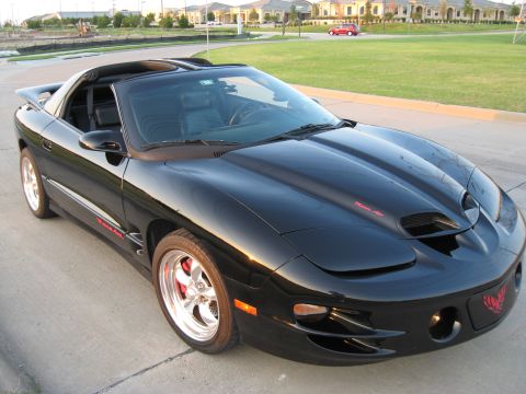 2002 Pontiac Trans Am - A black Pontiac Trans Am is shown from a 3/4 front angle, with a suburban neighborhood in the background.