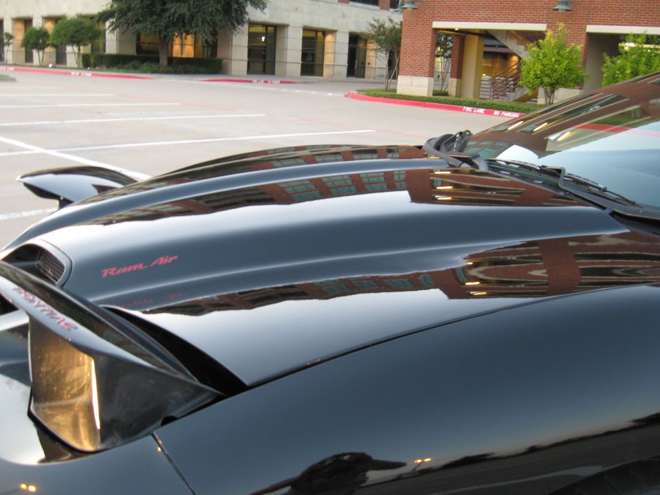 Black car hood with red 'Ram Air' badging and pop-up headlight