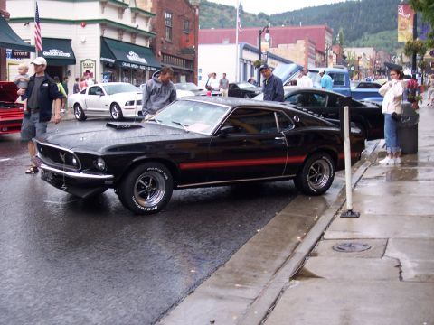 1972 Ford Ranchero - A classic black Mustang Mach 1 is displayed on a street during an event, with onlookers present.