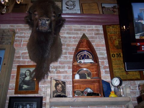 1972 Ford Ranchero - A taxidermied bison head is displayed prominently above a collection of framed pictures and decorative items on a brick wall.