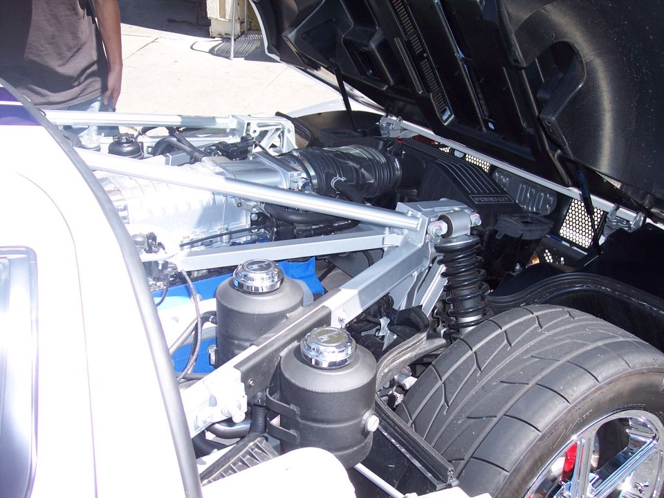Close-up of a supercharged V8 engine bay with a large intercooler and suspension components visible