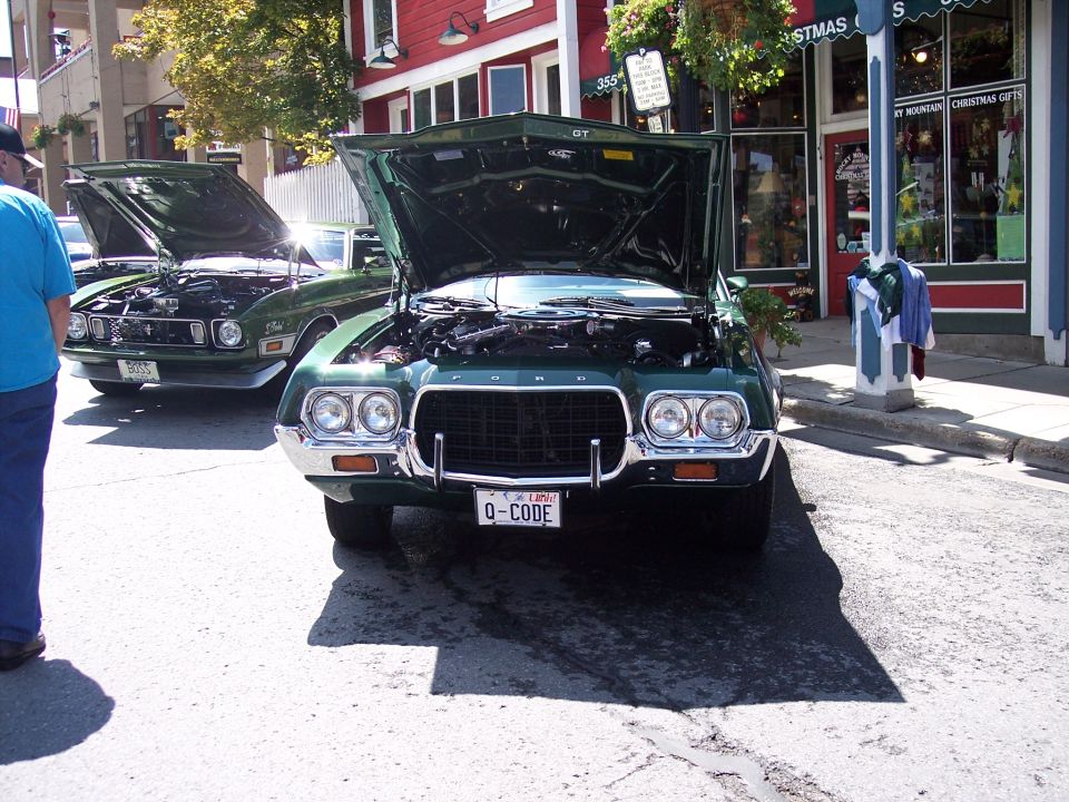 Green 1972 Ford Ranchero with hood open, parked on street